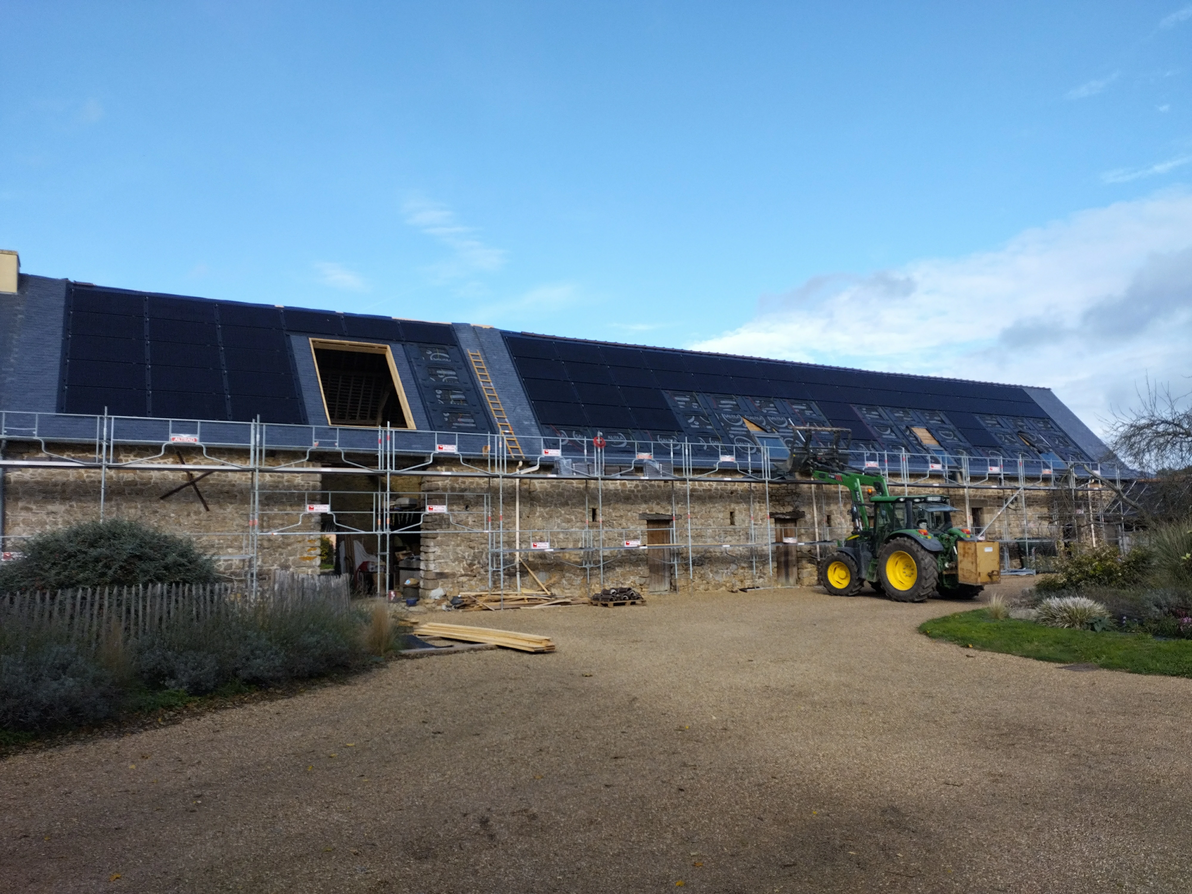 Installation d’une couverture en ardoise sur une grande structure agricole avec un échafaudage et des travaux en cours par Couverture Delalande.